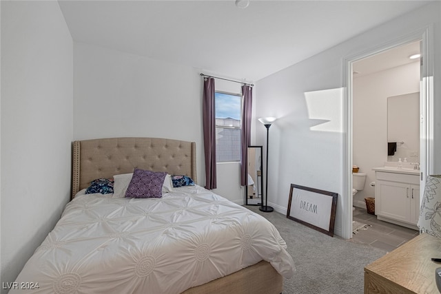 bedroom with ensuite bathroom, vaulted ceiling, and light hardwood / wood-style flooring