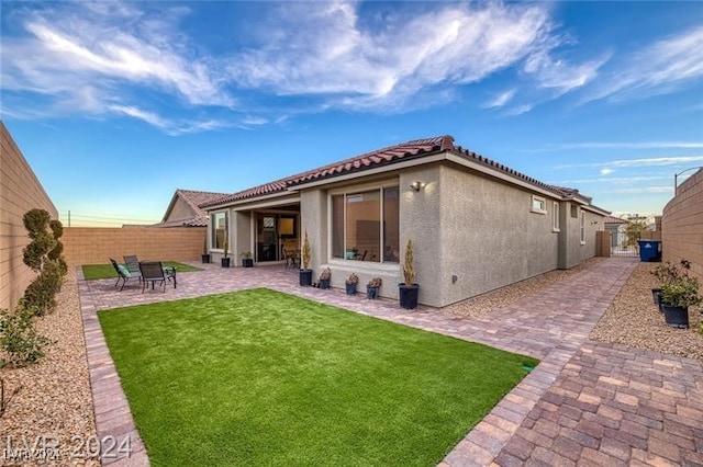 rear view of property featuring a patio area and a lawn