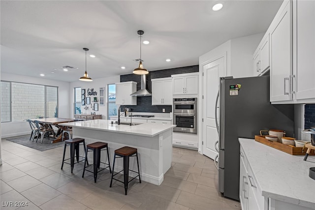 kitchen with a center island with sink, sink, white cabinets, and hanging light fixtures