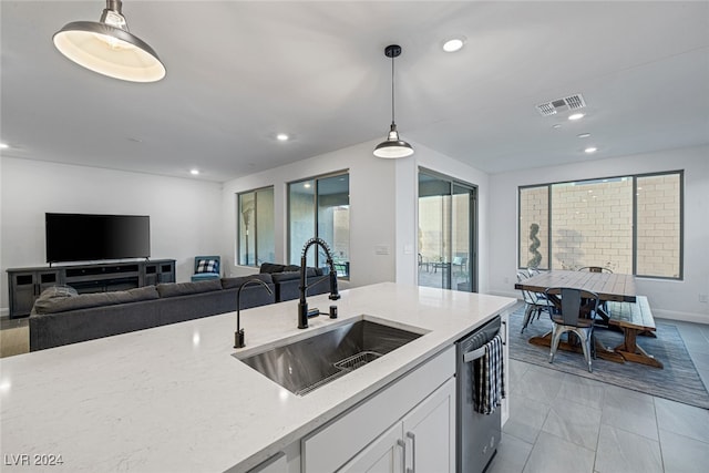 kitchen with light stone countertops, sink, hanging light fixtures, white cabinetry, and stainless steel dishwasher