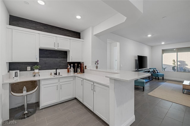 kitchen with sink, white cabinetry, kitchen peninsula, and a breakfast bar