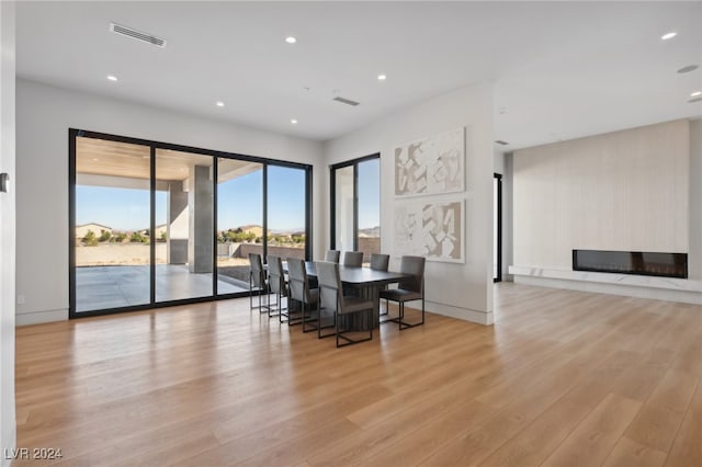 dining room featuring a large fireplace and light hardwood / wood-style floors