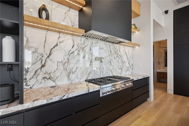 kitchen featuring range hood, decorative backsplash, stainless steel gas cooktop, light hardwood / wood-style floors, and light stone counters