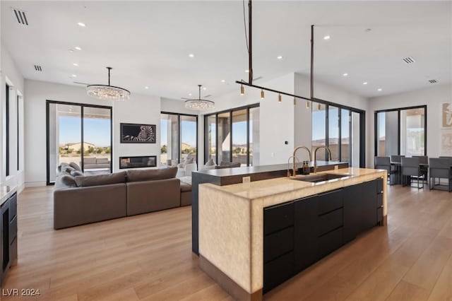 kitchen featuring decorative light fixtures, sink, a large island, a notable chandelier, and light wood-type flooring