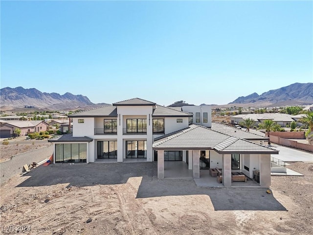 back of property with a mountain view and a patio