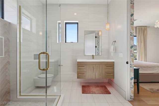 bathroom featuring a shower with door, vanity, tile walls, and toilet