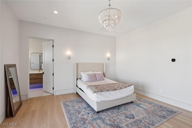 bedroom featuring a notable chandelier, wood-type flooring, and ensuite bathroom