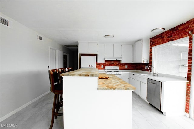 kitchen featuring white cabinets, sink, stainless steel dishwasher, white gas stove, and a kitchen island