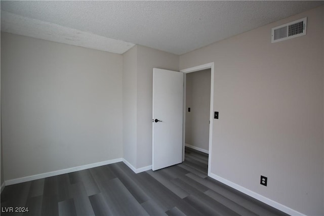 spare room with a textured ceiling and dark hardwood / wood-style floors