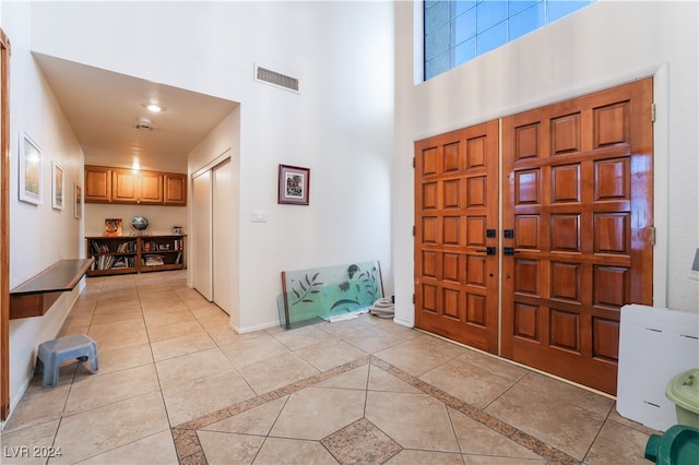 foyer entrance featuring a towering ceiling and light tile patterned floors