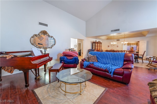 living room with high vaulted ceiling, wood-type flooring, and an inviting chandelier