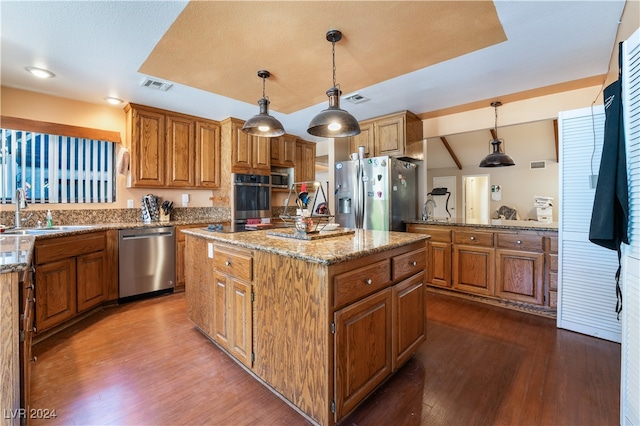 kitchen featuring stainless steel appliances, sink, pendant lighting, and a kitchen island