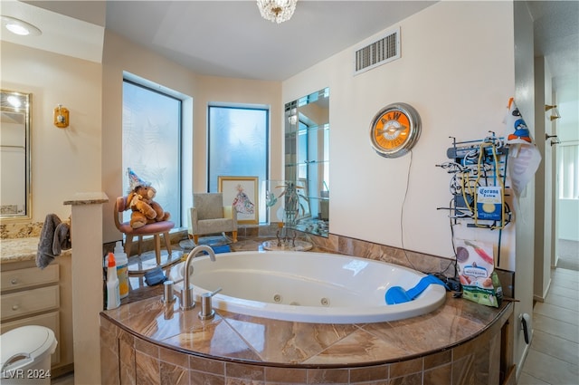 bathroom featuring vanity, a relaxing tiled tub, and tile patterned flooring