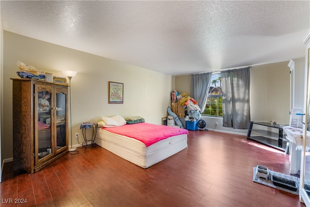 bedroom with a textured ceiling and dark hardwood / wood-style flooring