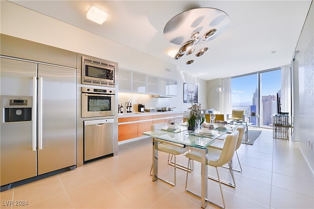 kitchen with built in appliances, expansive windows, white cabinetry, and light tile patterned floors