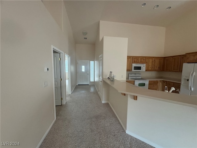 kitchen featuring a kitchen bar, kitchen peninsula, light carpet, high vaulted ceiling, and white appliances