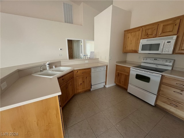 kitchen with kitchen peninsula, white appliances, sink, and light tile patterned floors