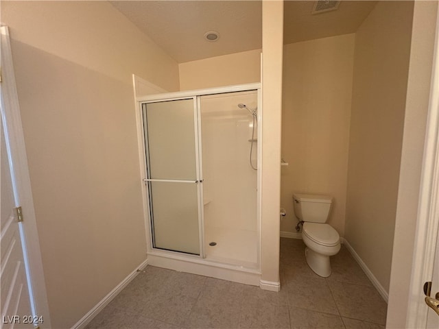 bathroom featuring toilet, tile patterned floors, and a shower with door