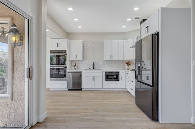 kitchen with white cabinets, stainless steel appliances, visible vents, and a sink