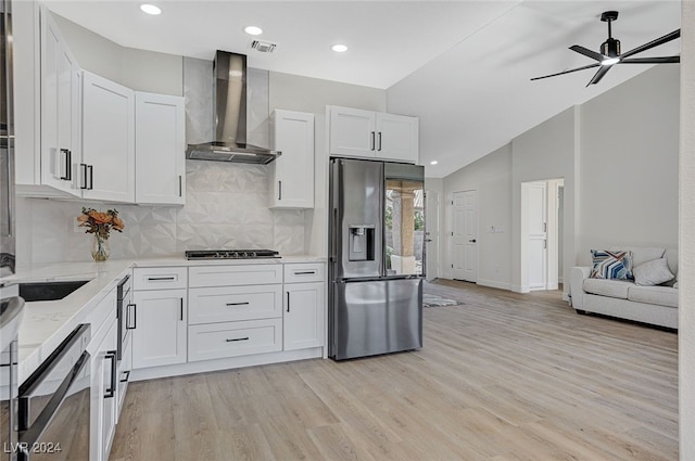 kitchen featuring wall chimney range hood, stainless steel fridge with ice dispenser, white cabinetry, and gas stovetop