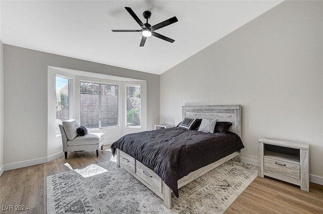 bedroom with ceiling fan, lofted ceiling, wood finished floors, and baseboards