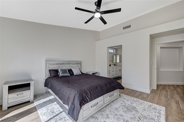 bedroom featuring a ceiling fan, wood finished floors, ensuite bathroom, baseboards, and visible vents