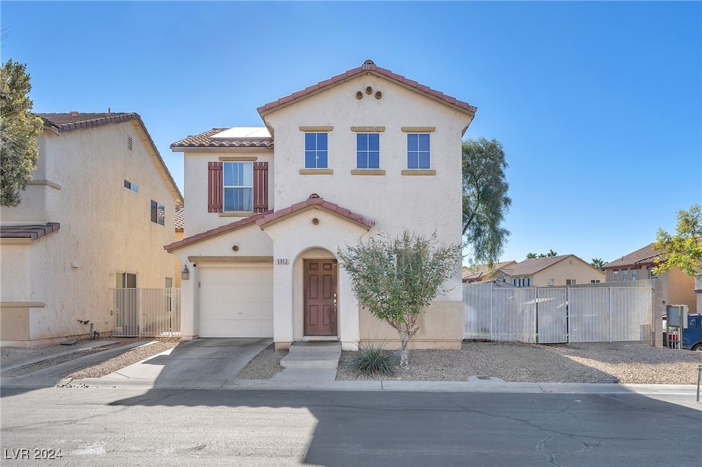 mediterranean / spanish-style home with concrete driveway, a tile roof, fence, and stucco siding