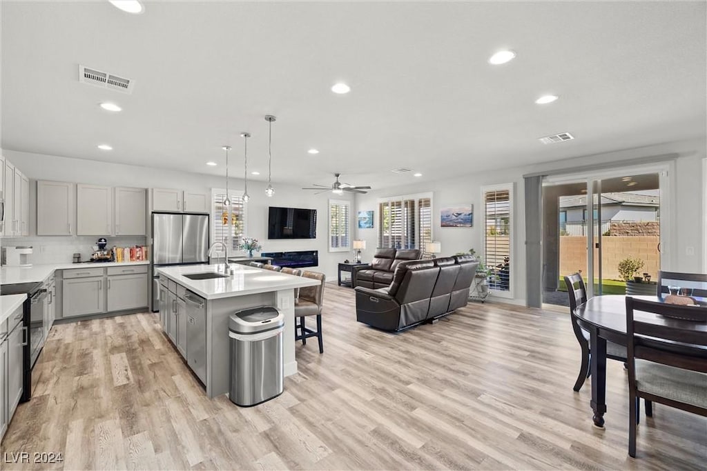 kitchen featuring gray cabinetry, pendant lighting, black electric range, ceiling fan, and an island with sink