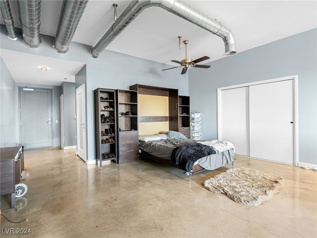 bedroom with ceiling fan, a high ceiling, two closets, and concrete flooring