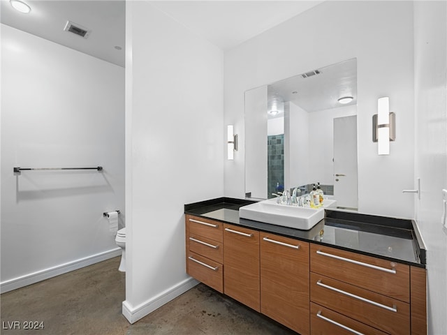 bathroom with concrete floors, vanity, and toilet