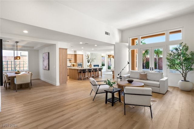 living room featuring a towering ceiling, french doors, and light hardwood / wood-style floors