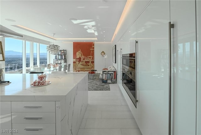 kitchen with white cabinets, light stone counters, light tile patterned floors, and modern cabinets