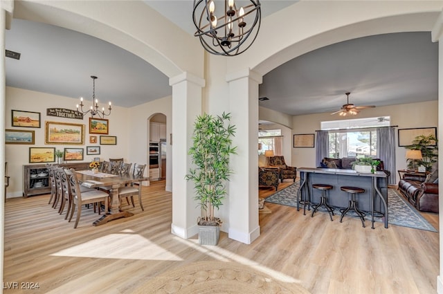 dining space featuring light hardwood / wood-style floors, ornate columns, and ceiling fan with notable chandelier