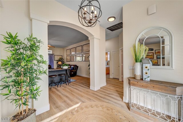 corridor with light hardwood / wood-style flooring and a chandelier