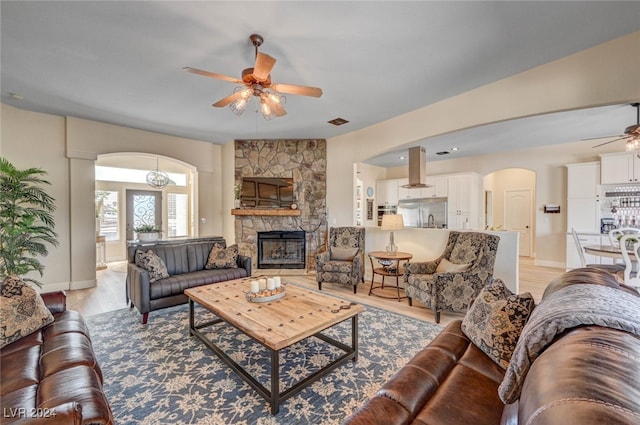 living room featuring sink, ceiling fan, light hardwood / wood-style flooring, and a fireplace