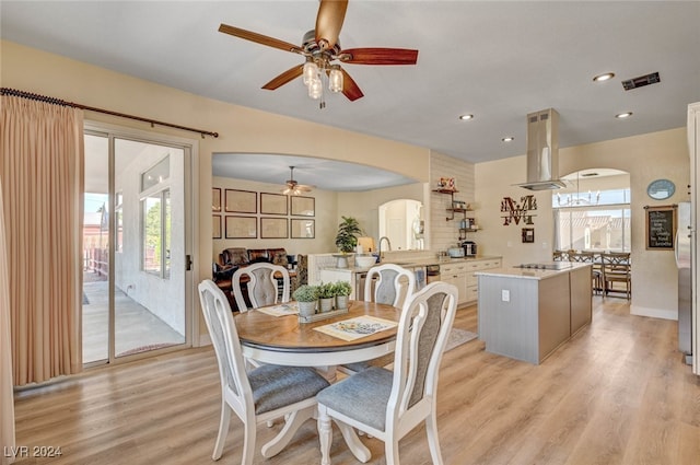 dining space with sink, light hardwood / wood-style flooring, and ceiling fan with notable chandelier