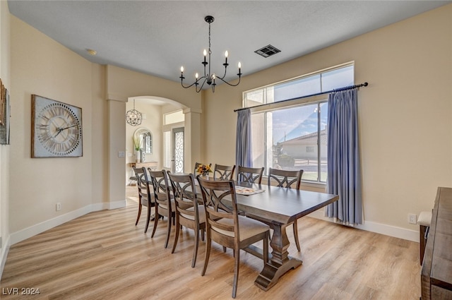 dining area with light hardwood / wood-style flooring, a textured ceiling, a chandelier, and ornate columns