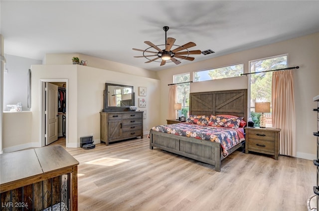 bedroom with a spacious closet, a closet, light wood-type flooring, and ceiling fan