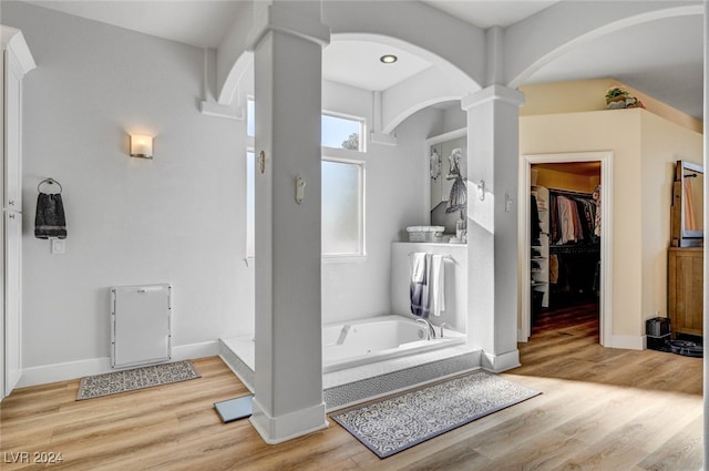 bathroom featuring ornate columns, wood-type flooring, and a bathing tub