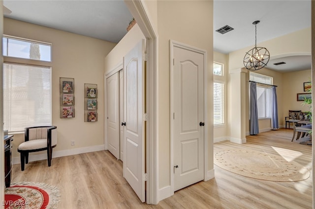 hall with light hardwood / wood-style flooring and an inviting chandelier