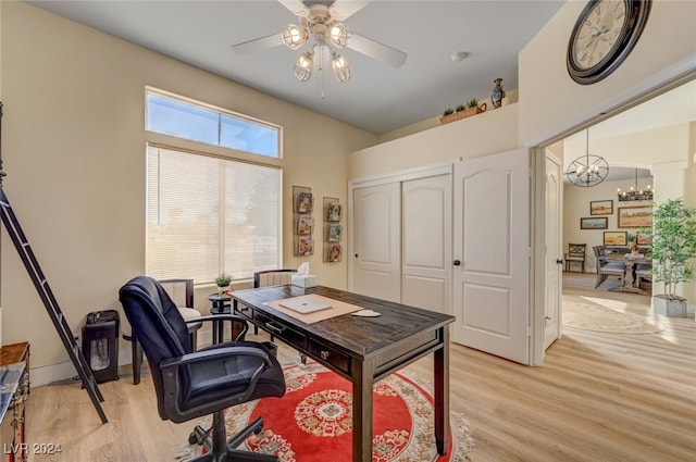 office area with light wood-type flooring and ceiling fan with notable chandelier