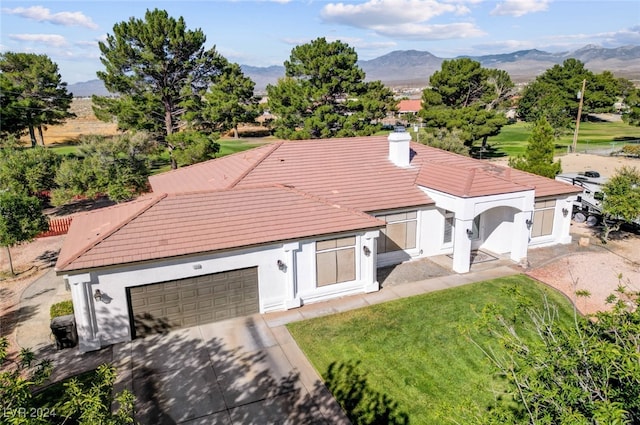 view of front facade with a garage, a mountain view, and a front lawn