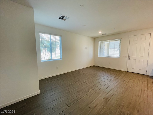 empty room with dark hardwood / wood-style flooring and a wealth of natural light