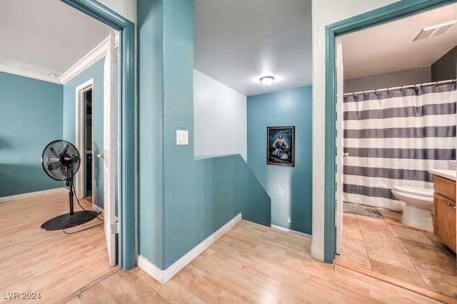 bathroom featuring toilet, hardwood / wood-style floors, crown molding, vanity, and a textured ceiling