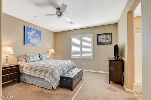 bedroom with ceiling fan, ensuite bath, and light colored carpet