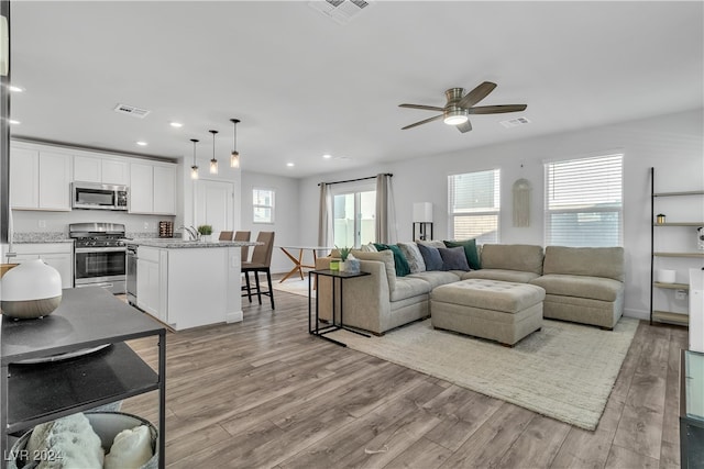 living room featuring light hardwood / wood-style flooring and ceiling fan