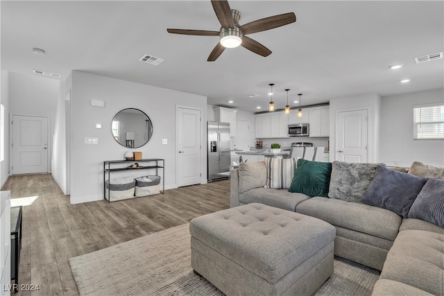 living room featuring light hardwood / wood-style floors and ceiling fan