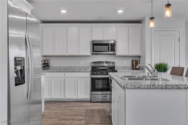 kitchen with appliances with stainless steel finishes, sink, light wood-type flooring, decorative light fixtures, and white cabinets