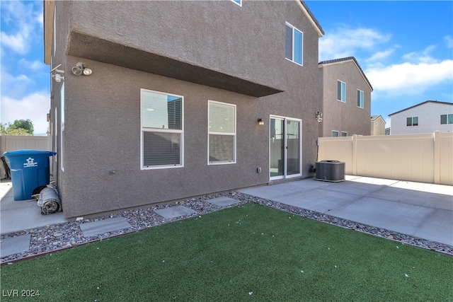 back of property with a yard, cooling unit, and a patio