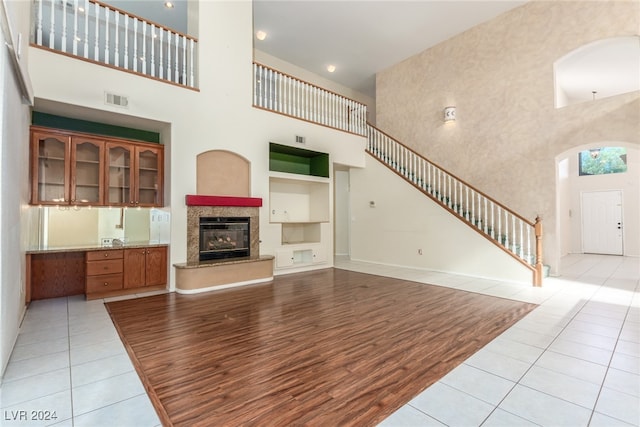 living room featuring built in features, light tile patterned floors, and a towering ceiling